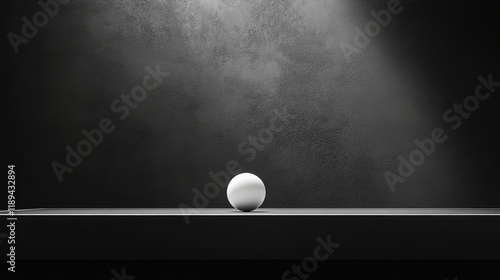 Light casts shadow on a single white ball resting on a dark surface