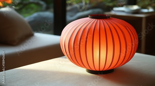 Red paper lantern placed on a wooden table in a bright room during daylight h...