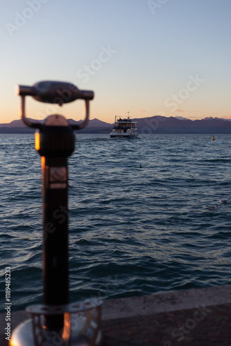 Obraz na płótnie Sunset view of a boat on calm waters, captured through an out-of-focus telescope, with mountains fading into the horizon. w salonie
