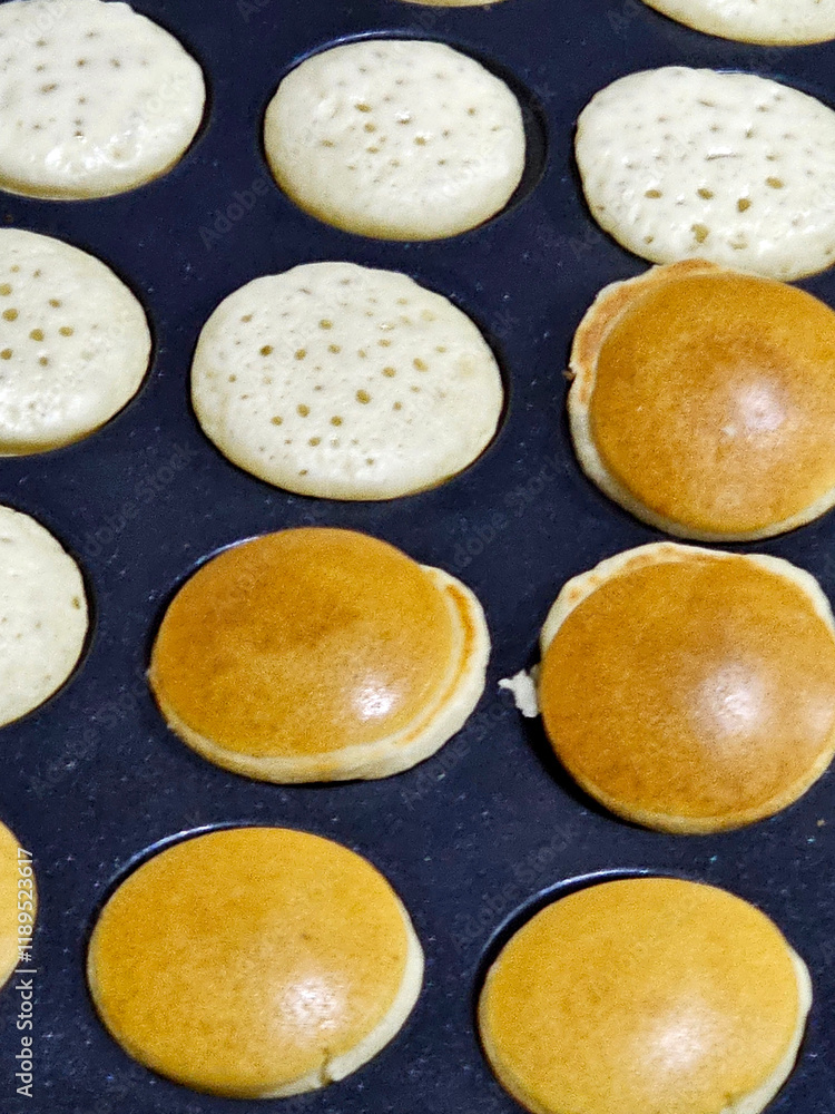 Hands preparing mini pancakes in a mold, they are turned over so that they are completely sewn for breakfast Hands preparing mini pancakes in a mold, they are turned over so that they are completely sewn for breakfast