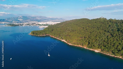Wallpaper Mural forested beach with boats in the blue sea and mountain backdrop under clear skies in Split, Croatia Torontodigital.ca