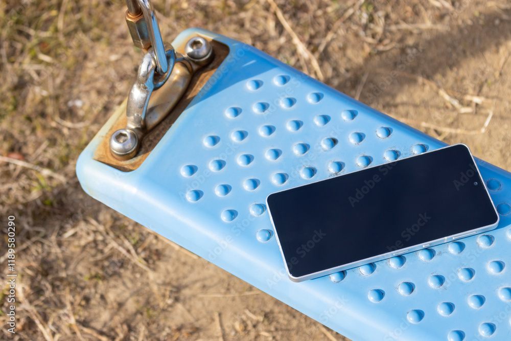 公園のブランコに忘れられたスマートフォン