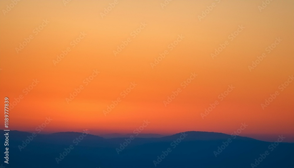 Fototapeta premium Fiery sunset over a distant mountain range.