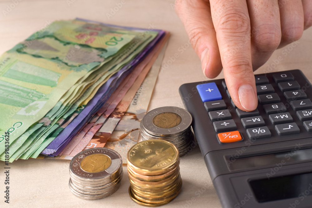 Closeup person's hand using calculator counting canadian cash money