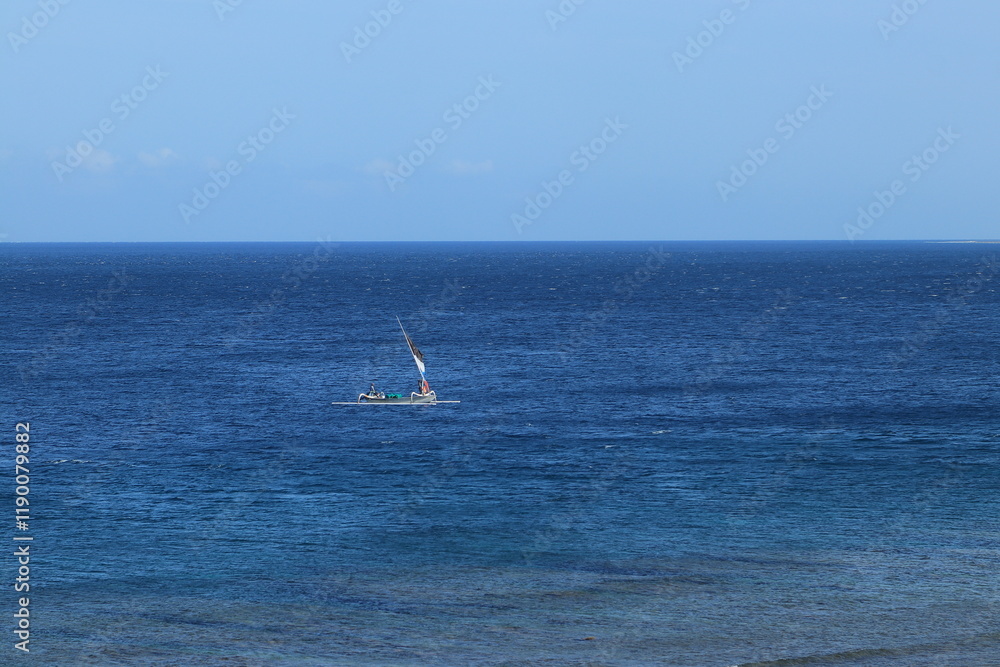 Sailboat Navigates Calm Blue Ocean with Clear Sky on a Tranquil Day Sailboat Navigates Calm Blue Ocean with Clear Sky on a Tranquil Day