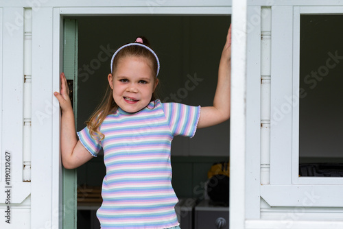 Little girl standing in play cubby house on farm with lymphatic malformation and speech disability photo