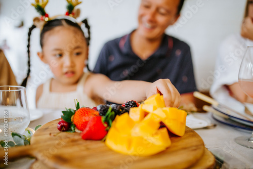 Closeup of fresh fruits on the wooden board with young Asian girl on the background. photo