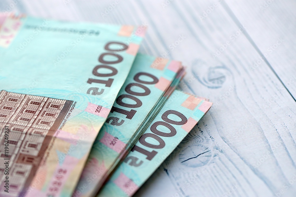 Big amount of ukrainian new one hundred hryvnia money bills with modern design on white wooden table. Financial concept, business Big amount of ukrainian new one hundred hryvnia money bills with modern design on white wooden table. Financial concept, business