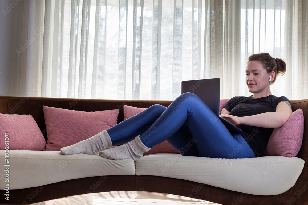 Young woman using laptop and wireless headphones at home Young woman using laptop and wireless headphones at home