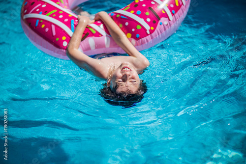 The boy is swimming on his back while holding an inflatable donut photo