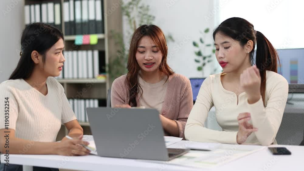 Professional women brainstorming at office desk. Coworker businesswoman engage in a lively discussion around a laptop in a modern office setting. Professional women brainstorming at office desk. Coworker businesswoman engage in a lively discussion around a laptop in a modern office setting.