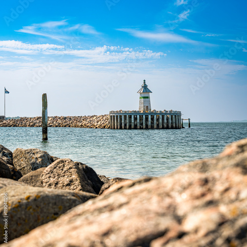 Blick auf das Signallicht West Mole Head light in der Hafeneinfahrt von Ebeltoft, im Vordergrund unscharf Steine der Küstenlinie, 1:1-Format photo