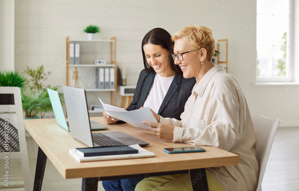 Coworkers working together in an office using a laptop and documents during a business meeting. Emphasizing collaboration, negotiation, and teamwork in a professional work setting. Coworkers working together in an office using a laptop and documents during a business meeting. Emphasizing collaboration, negotiation, and teamwork in a professional work setting.