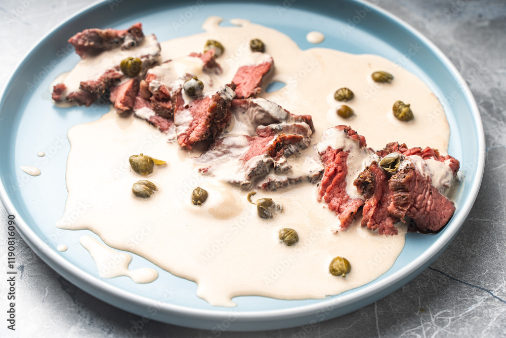 Vitello tonnato a traditional Italian dish of meat with tuna and anchovy cream sauce. Thin slices of beef in vitello tonnato sauce.Top view, close-up. High quality photo Vitello tonnato a traditional Italian dish of meat with tuna and anchovy cream sauce. Thin slices of beef in vitello tonnato sauce.Top view, close-up. High quality photo