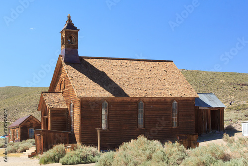 A small church with a steeple sits on a hill photo