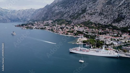 Drone scene of The Bay of Kotor with mountain view and a cruise ship behind the town photo