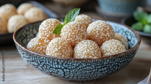 Delicious sweet dumplings served in a rustic bowl with sesame seeds on a wood...