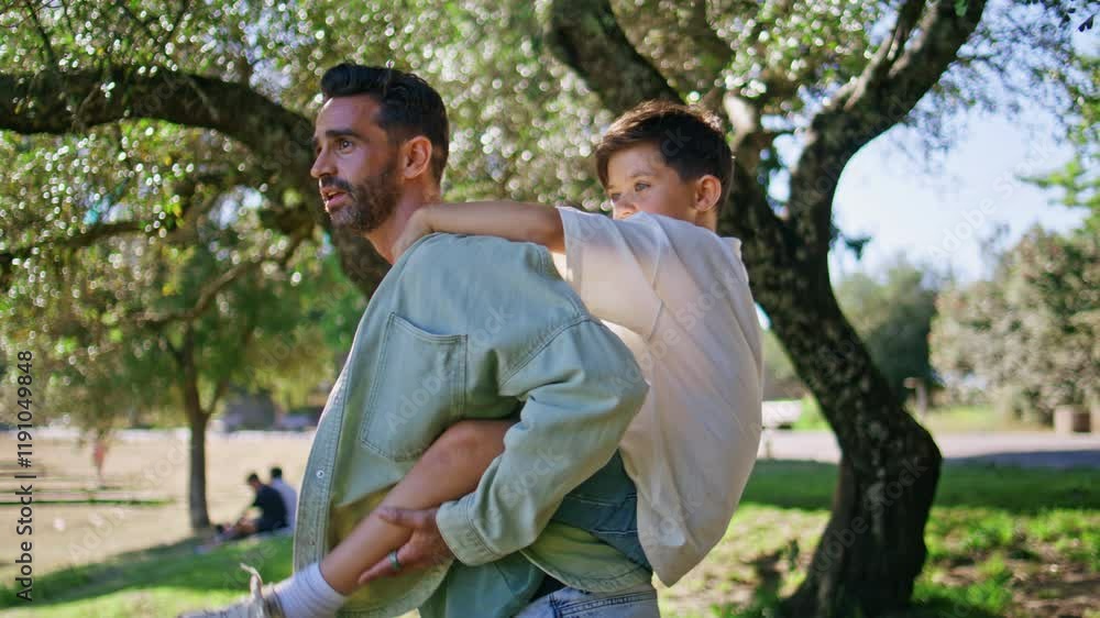 Brunette father holding kid at summer garden closeup. Joyful dad carrying son Brunette father holding kid at summer garden closeup. Joyful dad carrying son