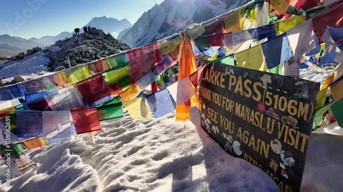Larke Pass, Nepal: The pass sign that lies at the summit of the Larke pass at 5106 and surrounded by Tibetan Buddhist flags along the Manaslu circuit trek in the Himalaya in Nepal