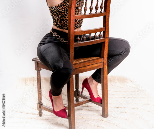 Corps de femme mince et sensuelle avec des hanches larges et un pantalon moulant assise à califourchon sur une chaise photo