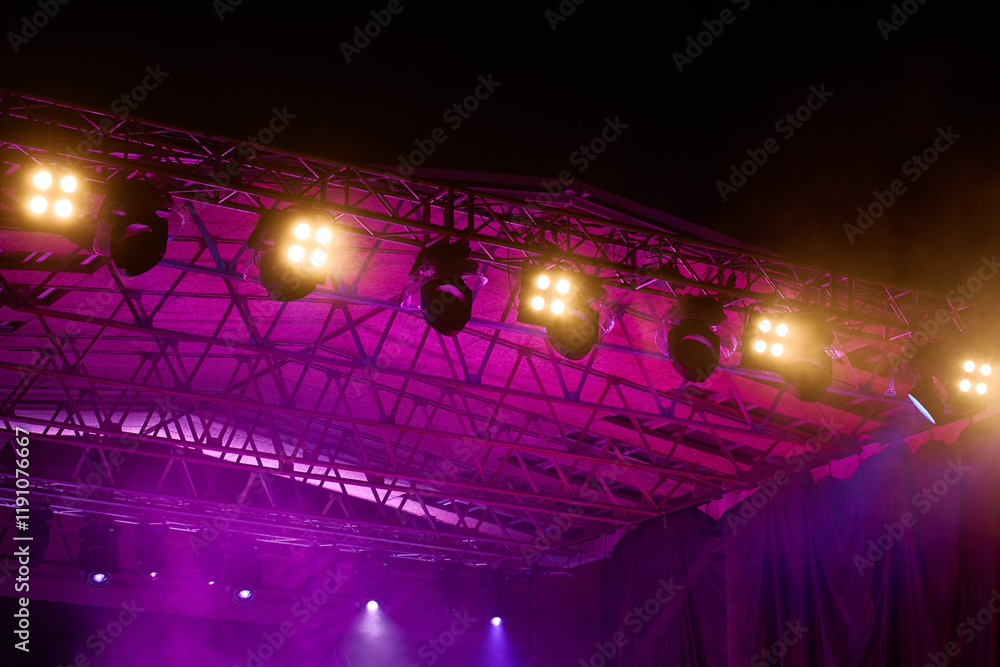 Close-up view of professional stage lighting mounted on metal truss. Bright spotlights at concert stage. Live music event