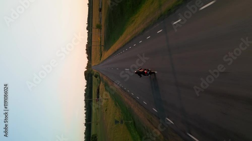 Bike driving on the road on sunset. Vertical video. Drone
