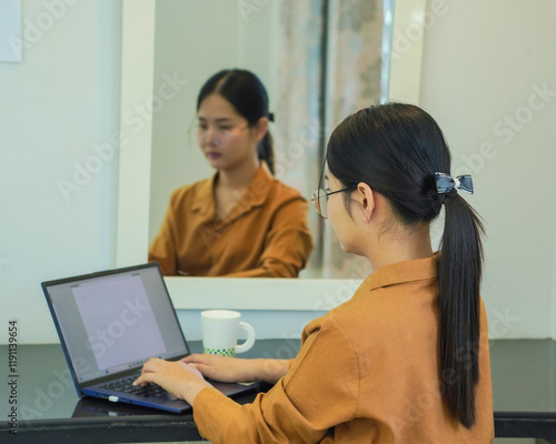 Business people. Businesswoman working online on laptop screen at house, working from home. Using computer website. An Asian woman in a long-sleeved shirt, dressed neatly, is sitting and working happy photo