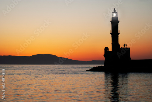 A couple in love holding hands by a lighthouse during sunset, Copy space for additional content.
