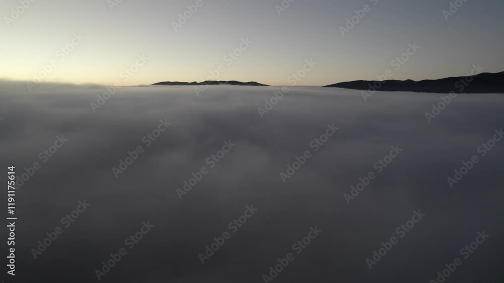 Paisaje invernal en montaña a vista de drone con sol de fondo y nubes bajas Paisaje invernal en montaña a vista de drone con sol de fondo y nubes bajas