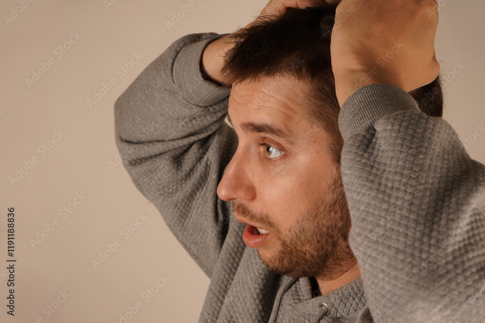Obraz premium Holding his hair in his fist, the man shows clear signs of tension or stress. His face reflects a moment of suffering. The pose creates an irresistible feeling of mental tension.