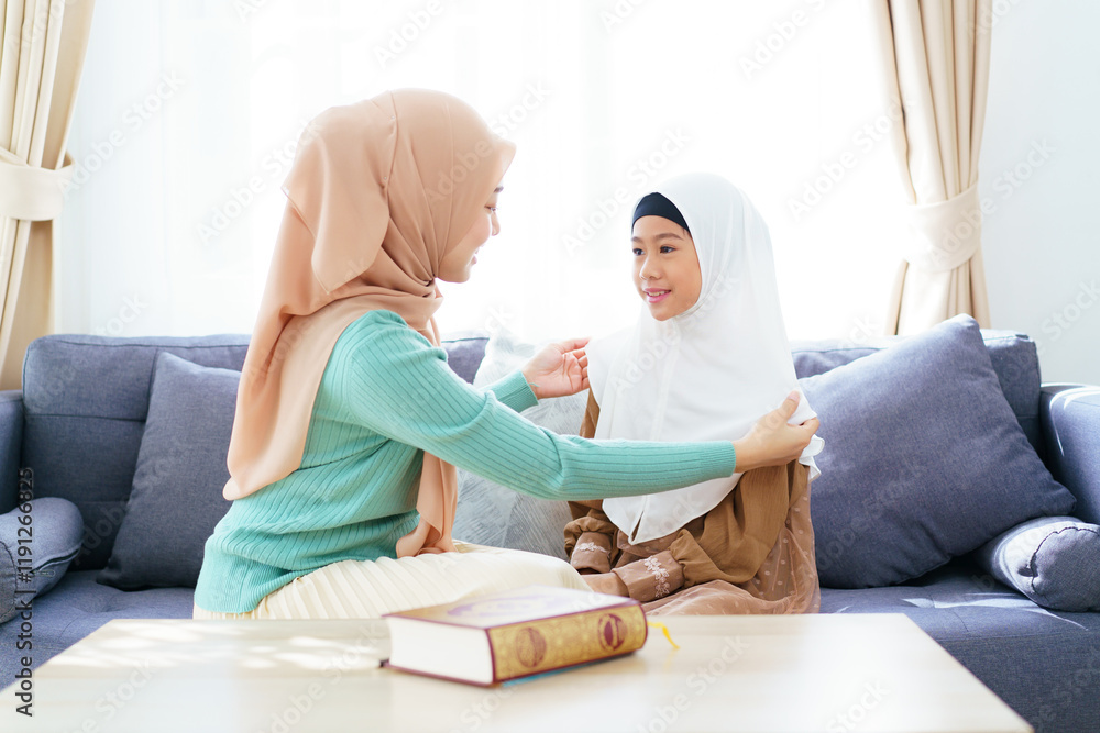 Obraz premium Asian muslim family's lifestyles concept. Woman get her daughter dressed.