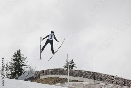 Professional male athlete performing ski jumping, flying through the air during training.
