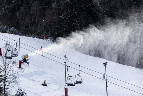 Obraz na płótnie Snow making in a mountain resort. Beautiful view with snow cannons powered on to create snow from water and to keep the slopes available for tourists. w salonie