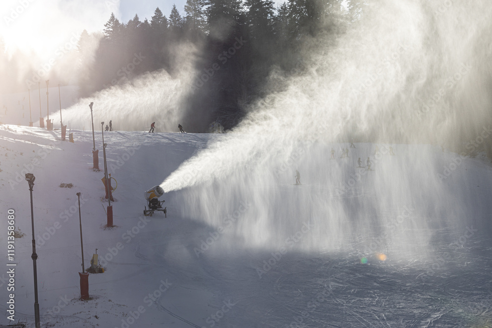 Snow making in a mountain resort. Beautiful view with snow cannons powered on to create snow from water and to keep the slopes available for tourists.