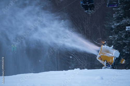 Obraz na płótnie Snow cannon in the evening. Snow making machine on ski slope in the evening to prepare the mountain ski resort for the next day. Winter sports industry. w salonie