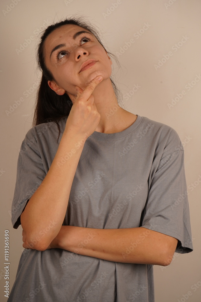 A calm pose, symbolizing mindfulness and reflection. A young woman places her hand under her chin, deep in thought. Her gaze is focused, reflecting contemplation and introspection. A calm pose, symbolizing mindfulness and reflection. A young woman places her hand under her chin, deep in thought. Her gaze is focused, reflecting contemplation and introspection.