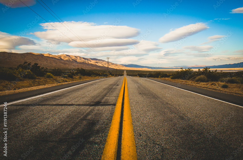 Naklejka premium Prosta droga przez pustynny krajobraz pod błękitnym niebem