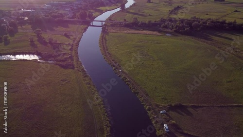  View of a Beautiful  River at Sunset Surrounded by Green Fields Drone Aerial 4K Slow Motion