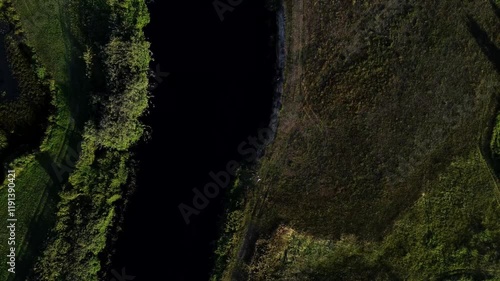 View of a Beautiful  River at Sunset Surrounded by Green Fields Drone Aerial 4K Slow Motion