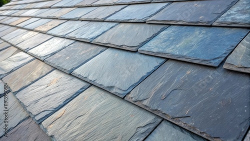 A medium closeup of synthetic roofing tiles that mimic slate revealing intricate details like a rough layered texture and shades of slate gray interspersed with hints of blue