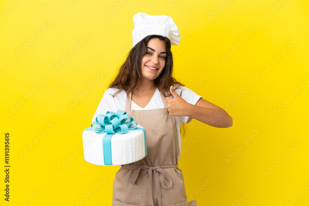 Young caucasian pastry chef woman with a big cake isolated on yellow background giving a thumbs up gesture Young caucasian pastry chef woman with a big cake isolated on yellow background giving a thumbs up gesture