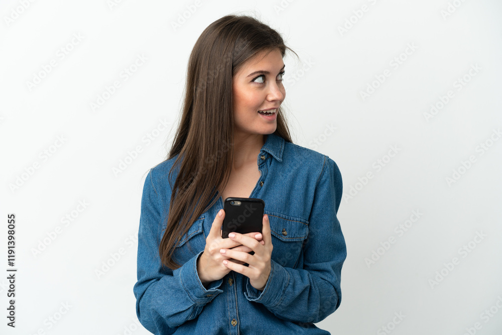 Young caucasian woman isolated on white background using mobile phone and looking up Young caucasian woman isolated on white background using mobile phone and looking up