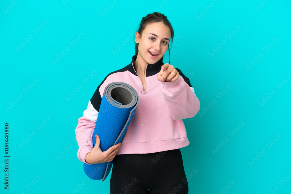 Sport Ukrainian woman going to yoga classes while holding a mat surprised and pointing front Sport Ukrainian woman going to yoga classes while holding a mat surprised and pointing front
