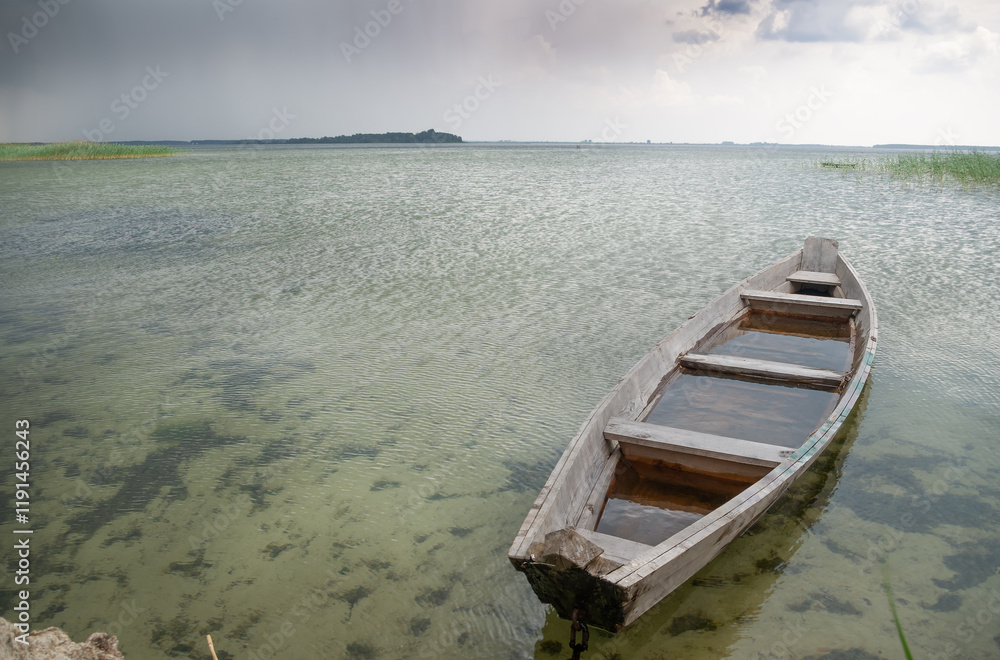 one wooden boat moored to the shore of a lake one wooden boat moored to the shore of a lake