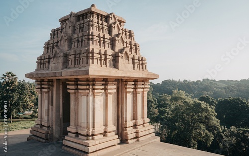 Ancient stone temple structure with intricate carvings, situated on a hilltop overlooking lush greenery under a clear sky. photo