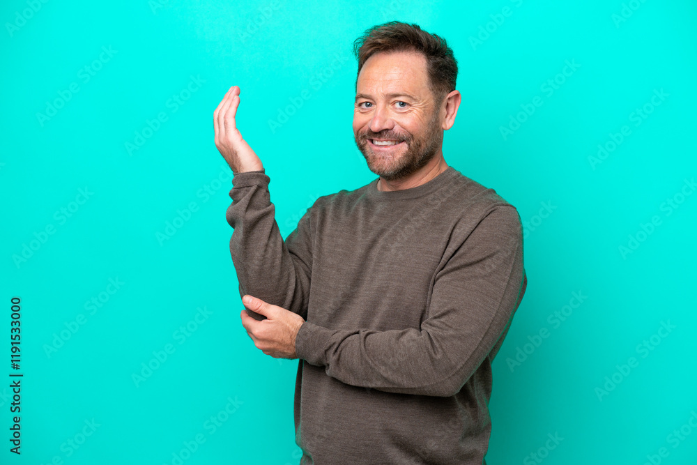 Middle age caucasian man isolated on blue background extending hands to the side for inviting to come Middle age caucasian man isolated on blue background extending hands to the side for inviting to come