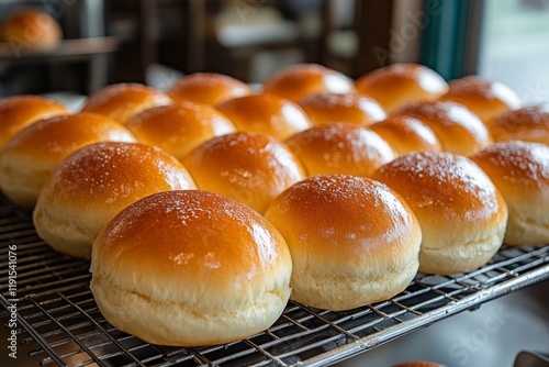 Freshly baked golden bread rolls cooling on a wire rack in a bakery kitchen
