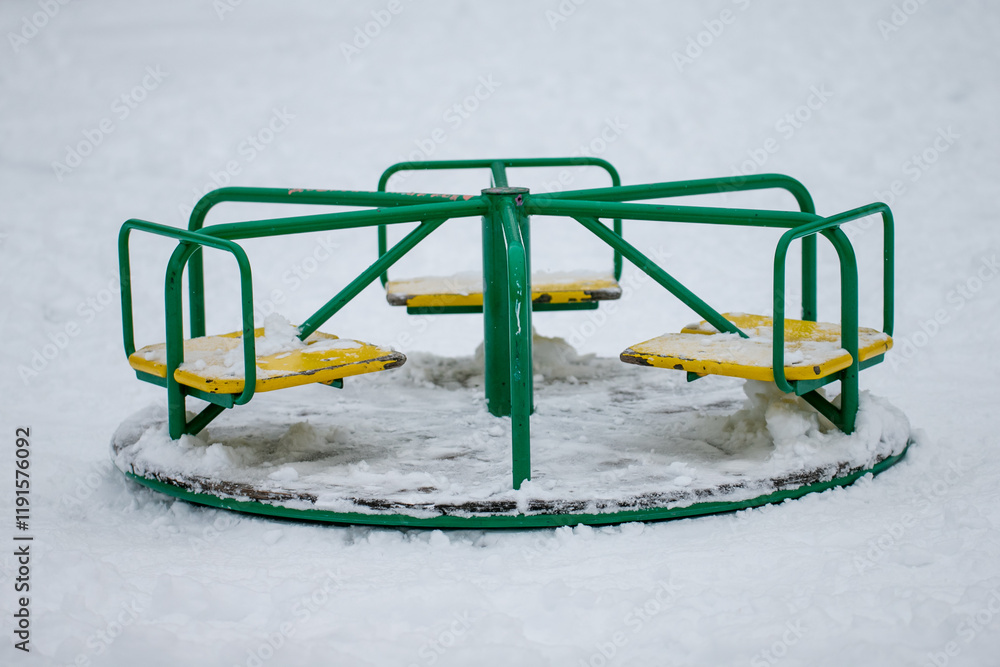 In winter snow covered roundabout, merry go round carousel at playground in green color In winter snow covered roundabout, merry go round carousel at playground in green color