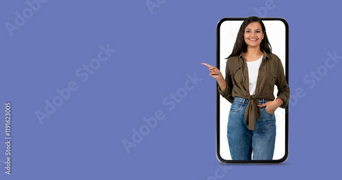 A woman with a friendly expression is interacting with a large smartphone. She points towards the screen while showcasing the engaging communication features of modern technology. photo