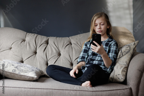 Portrait of girl Playing Game on phone. Relaxing in Living Room
